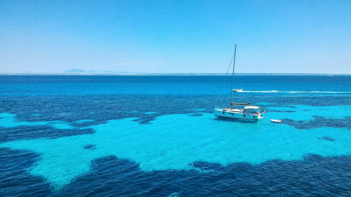 Turquoise water and a yacht off Bue Marino, Favignana, Sicily