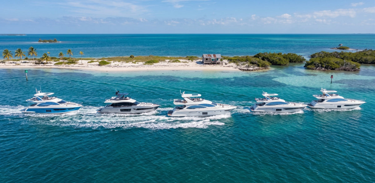 Five luxury yachts cruising together beside a tropical island